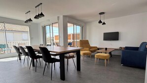 A modern living space with a dining area, a sofa, and a TV mounted on the wall. - Apartment near the beach - 6 guests (Saint-Hilaire-de-Riez)