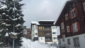 Un carrer nevàt amb un edifici modern anomenat 'Sunnybank' i arquitectura tradicional.