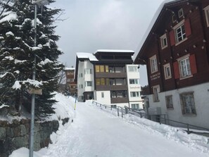 Eine verschneite Straße mit einem modernen Gebäude mit der Aufschrift 'Sunnybank' und traditioneller Architektur.