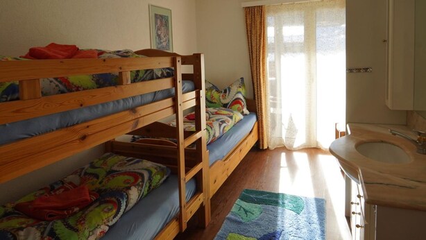 Habitació amb lliteres, finestra, bany amb bateda i una catifes amb dibuixos.