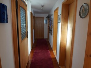 A hallway with wooden doors, a red carpet, and a ceiling fan. - Sunnybank / 2. St. Appartement/Fewo, Dusche und Bad, WC, 9-Bettwohnung by Interhome (Arosa)