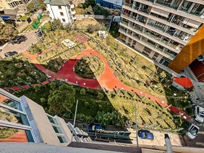 Vue aérienne d’un quartier urbain moderne, avec un espace vert central, des allées et des bâtiments environnants.