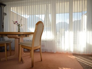 Quarto com mesa de jantar de madeira, uma cadeira e um vaso com flores.