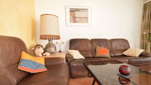A living room with two brown leather sofas, a coffee table, a lamp, and a framed picture on the wall. - Gentiana C-7 Appartement/Fewo, Dusche und Bad, WC, 2-Bettwohnung by Interhome (Arosa)