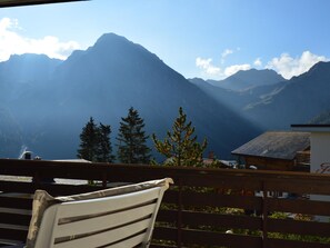 Un banc de fusta amb vista a un paisatge montanyós sota un cel serè.