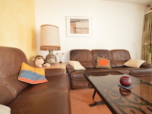 A living room with a brown leather sofa, a glass coffee table, and a lamp with a textured lampshade. - Gentiana C-7 Appartement/Fewo, Dusche und Bad, WC, 2-Bettwohnung by Interhome (Arosa)