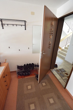 A room with a wooden door, a shoe rack, a mirror, and a patterned rug. - Gentiana C-7 Appartement/Fewo, Dusche und Bad, WC, 2-Bettwohnung by Interhome (Arosa)