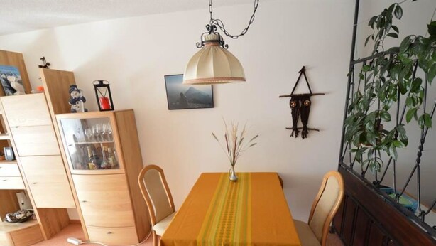 A dining area with a table, chairs, a hanging lamp, a cabinet, and a plant. - Gentiana C-7 Appartement/Fewo, Dusche und Bad, WC, 2-Bettwohnung by Interhome (Arosa)