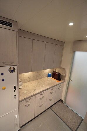 Una cocina con refrigerador integrado, microondas y cafetera sobre la encimera.