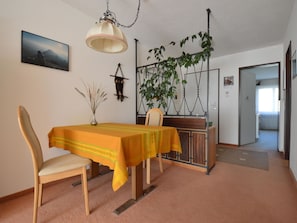 A dining area with a table set for two, a hanging plant, and a painting on the wall. - Gentiana C-7 Appartement/Fewo, Dusche und Bad, WC, 2-Bettwohnung by Interhome (Arosa)