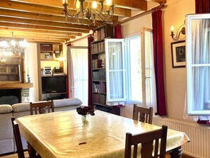 Ein gemütlicher Essbereich mit Tisch, Stühlen, einer Chandelüster, einem Bücherregal und einem Kamin.