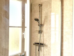 Ein Badezimmer mit Dusche, Fenster und Tür.