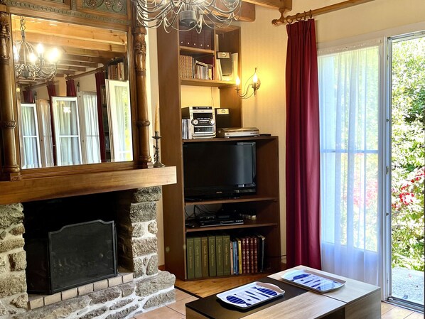 Ein Wohnzimmer mit Kamin, Fernseher, Bücherregalen und einem Tisch mit Papieren.