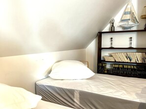 Ein Schlafzimmer mit einem Bett, einem Bücherregal und einem kleinen dekorativen Segelboot.