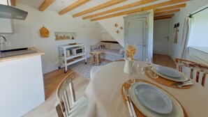 A dining area with a table set for two, a kitchen with a microwave and a sink, and a loft bedroom with a staircase. - Cozy T2 apartment with terrace - 2 guests (BOIS D'AMONT)