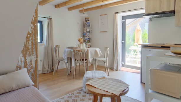 A cozy room with a bed, a dining table with chairs, a small stool, a kitchen area with cabinets, and a view of the outside. - Cozy T2 apartment with terrace - 2 guests (BOIS D'AMONT)