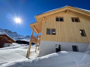 A wooden chalet with a balcony, a snow-covered landscape, and mountains in the background. - Chalet Sternenhimmel Appartement/Fewo, Dusche und Bad, WC, 7-Bettwohnung by Interhome (Arosa)