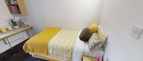 A small, neatly arranged bedroom with a bed, bedside table, and a shelf with decorative items.