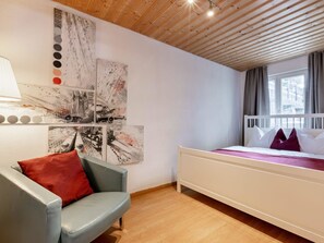 Ein Schlafzimmer mit einem Bett, einem Sessel und Bildern an der Wand.
