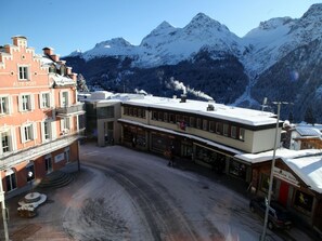 Un hotel con techo nevado, entrada visible y montañas al fondo.