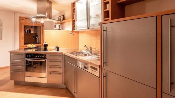 Una cocina moderna con horno integrado, un lavamanos y un refrigerador de acero inoxidable.