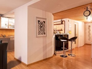 A modern kitchen with a dining area, a bar, and a clock on the wall. - SKA Haus Appartement/Fewo, Dusche und Bad, WC, 6-Bettwohnung by Interhome (Arosa)