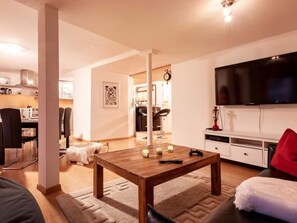 Una sala de estar moderna con una mesa de centro de madera, un televisor de pantalla plana y un sofá.