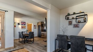 Eine moderne Küche mit Essbereich, Holzboden und Regalen an der Wand mit Dekoration.