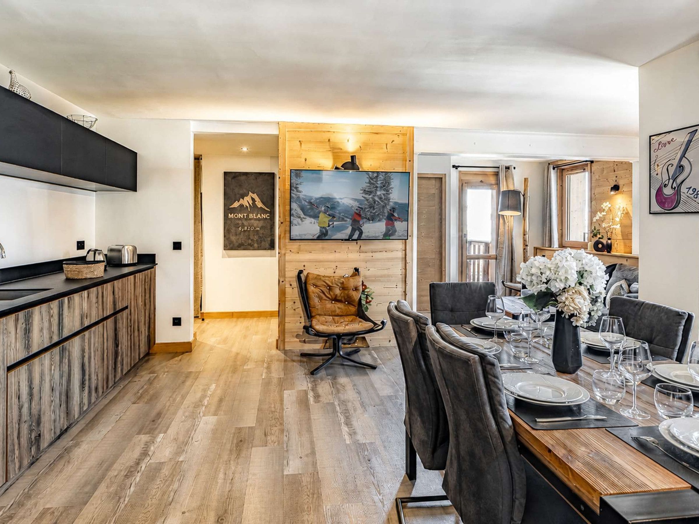 A modern kitchen with a wooden countertop and a dining area with a wooden table set for four.