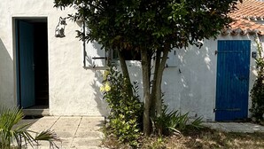 Ein Gebäude mit einer blauen Tür, einer weißen Wand und einem Baum davor.