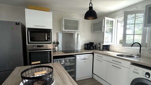 Eine kleine Küche mit Mikrowelle, Backofen, Geschirrspüler und Waschmaschine.