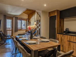 A dining area with a wooden table set for four, a sofa, and a coffee machine. - Central duplex, sauna - 8 guests (Belle Plagne)