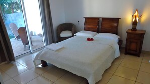 Habitación de hotel con una cama, una silla, una mesita de noche y vistas a través de un ventanal.