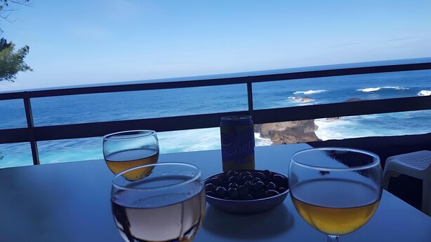 A table with two glasses of a yellow beverage, a can of beer, and a bowl of olives, overlooking the ocean. - Villas Manapany – Villa Le Jacquier: 3★ Seaside Comfort in La Réunion (Saint Joseph)
