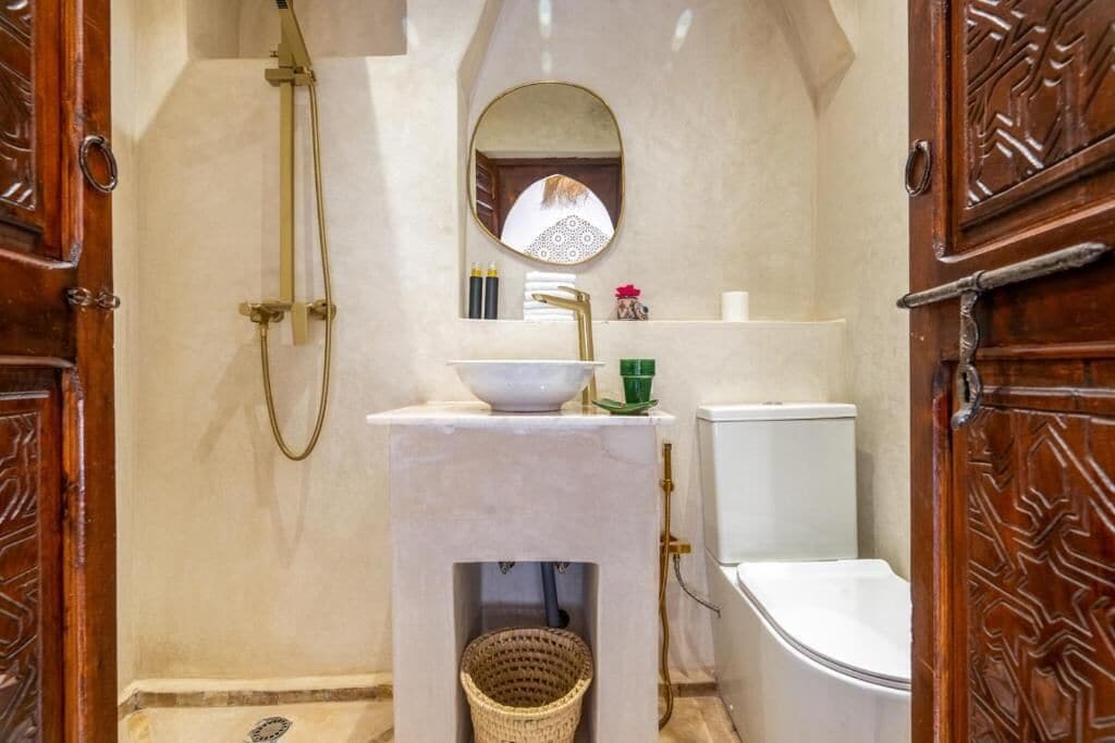 A bathroom with a marble sink, a mirror, a shower, and a toilet.