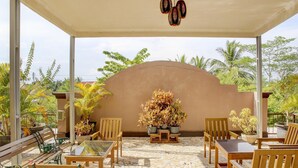 A covered outdoor seating area with wooden furniture and potted plants.