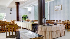 A dining area with round tables, wooden chairs, and a large pillar.
