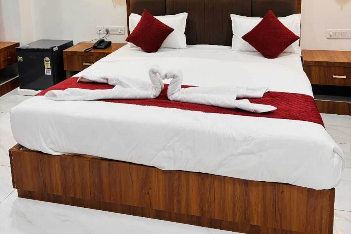 A hotel room with a large bed, two bedside tables, a ceiling fan, and wall-mounted lamps.
