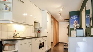 A modern kitchen with white cabinets, a built-in oven, and a coffee machine. - Rothornblick 8 Appartement/Fewo, Bad, WC, 4-Bettwohnung by Interhome (Arosa)