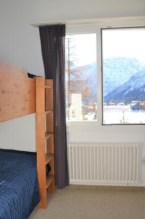 A room with a bunk bed, a window with a view of mountains, and a radiator. - Bisang S Appartement/Fewo,   4-Bettwohnung by Interhome (Arosa)