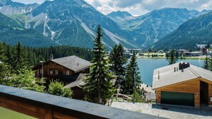 Uma cabana na montanha com vista para um lago e montanhas.