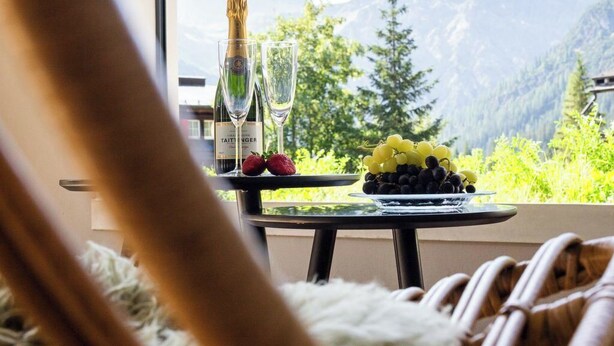 Blick vom Balkon mit Tisch, darauf eine Flasche, Gläser, Erdbeeren und Trauben.