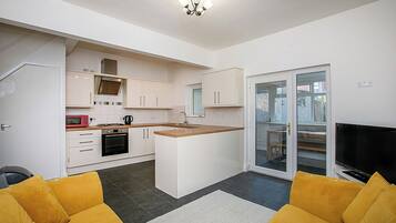 A compact kitchen with white cabinets, a microwave, and a stove. There's a small island with a sink, and a sliding glass door leading to a balcony.