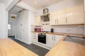 A modern kitchen with white cabinetry, a stainless steel sink, a microwave, and a stove.