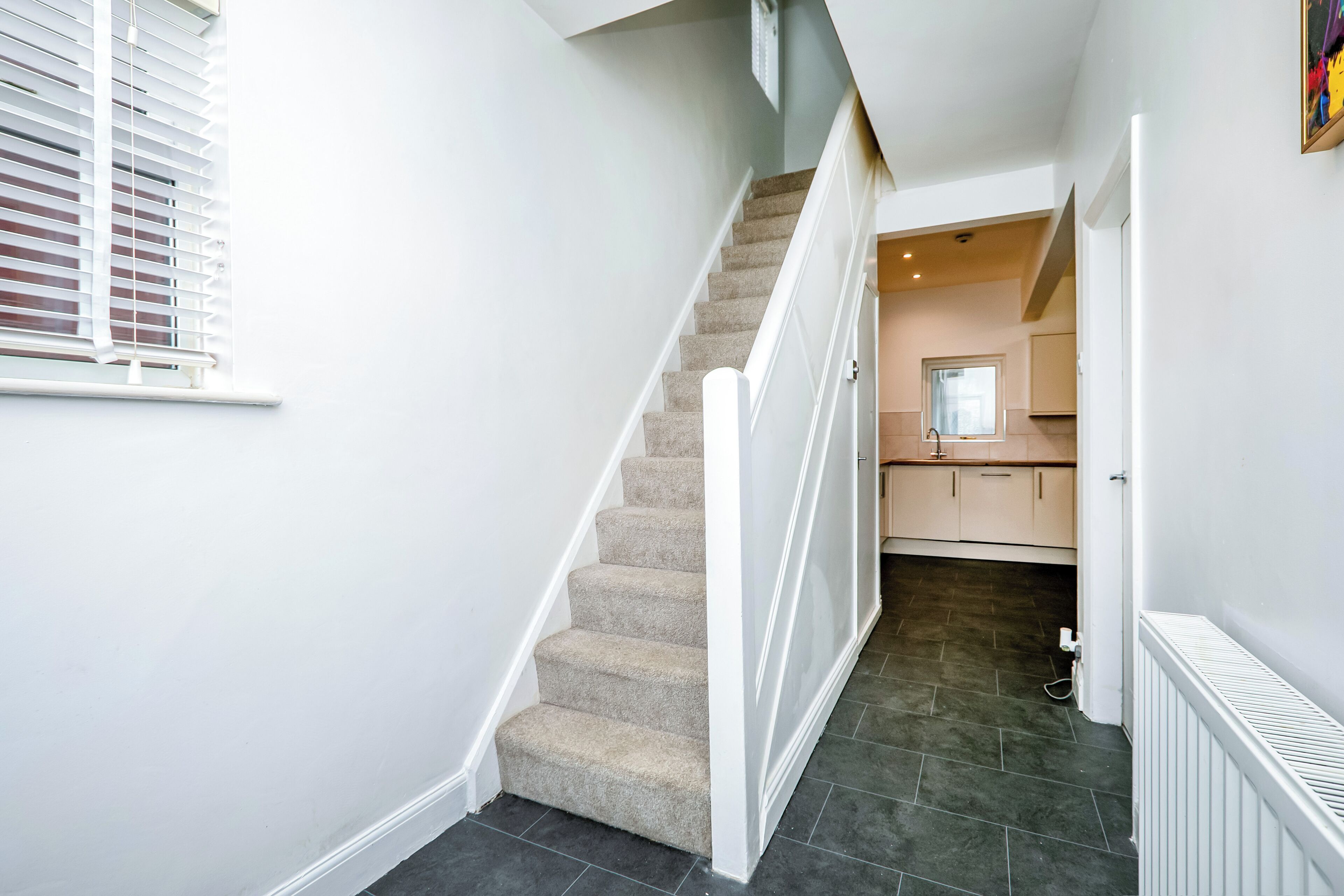 A staircase leading to a kitchen area with a radiator on the floor.