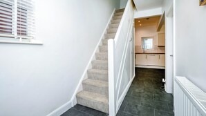 Una escalera que lleva a una zona de cocina con un radiador en el suelo.
