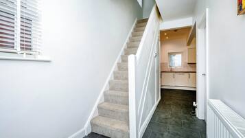 A staircase leading to a kitchen area with a radiator on the floor.