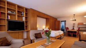 Un salon moderne comprenant un canapé, un fauteuil, une table basse en bois, un téléviseur et un coin repas avec des chaises et une table.