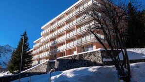Un hôtel à plusieurs étages, doté de balcons, d’une base en pierre et entouré de neige.