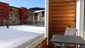 A balcony with a wooden floor, metal railing, and a table with chairs. - Waldhof 1 by Arosa Holiday Appartement/Fewo, Dusche, WC, 2-Bettwohnung Waldhof 1 by Interhome (Arosa)